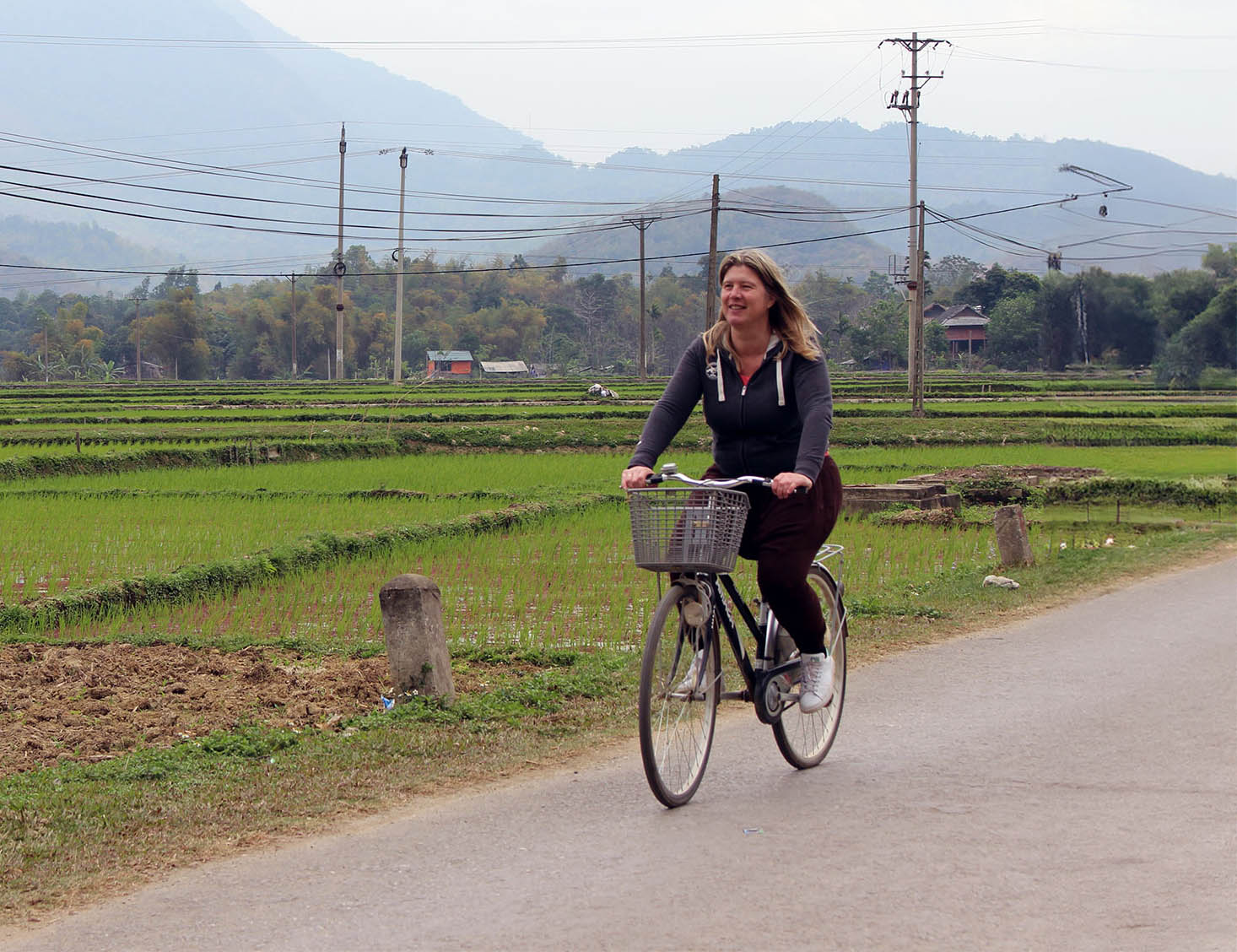 Danielle lachend op de fiets door rijstvelden.